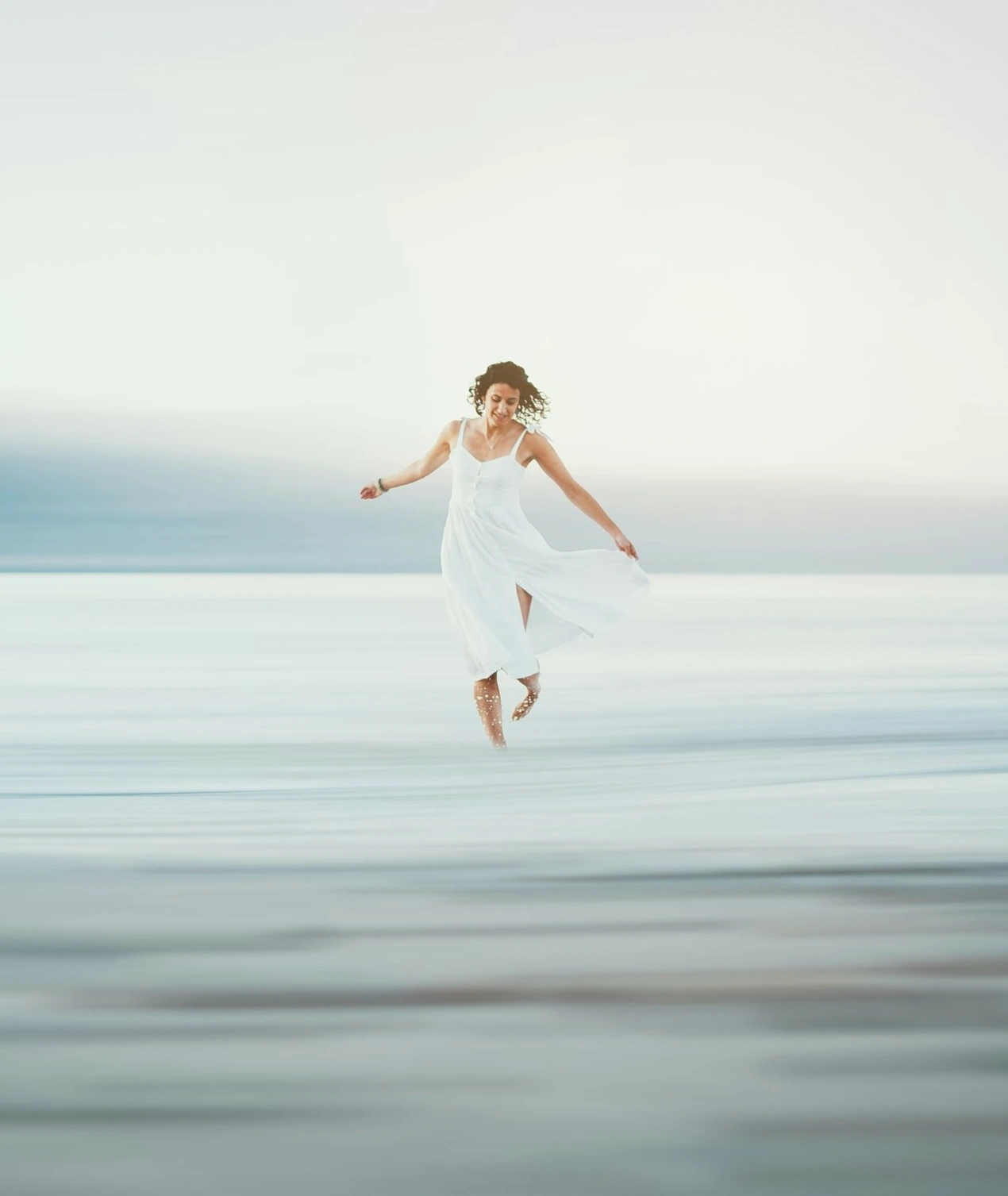 a woman in a white dress jumping in the air